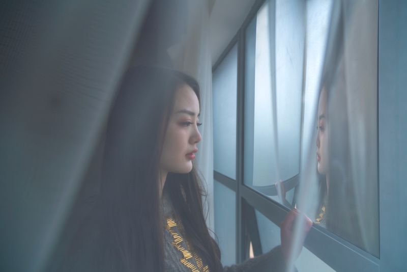 A person pausing thoughtfully by a window